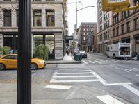 this is an intersection where yellow cabs are passing by a building and shops on the road