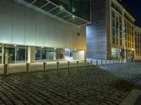 large building with windows in an empty street with brick walkways at night time,