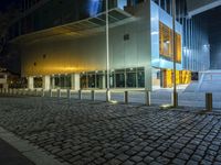 large building with windows in an empty street with brick walkways at night time,