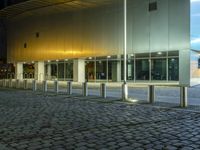 large building with windows in an empty street with brick walkways at night time,