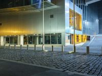 large building with windows in an empty street with brick walkways at night time,