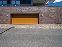 a yellow garage door sitting in front of a building and brick wall on the side