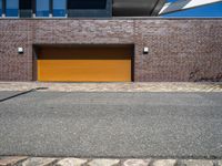 a yellow garage door sitting in front of a building and brick wall on the side