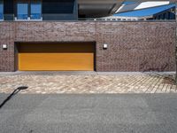 a yellow garage door sitting in front of a building and brick wall on the side