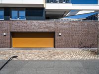 a yellow garage door sitting in front of a building and brick wall on the side