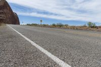 a single yellow painted line on a highway near mountains and rocks and boulders that look like they are melting