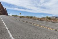 a single yellow painted line on a highway near mountains and rocks and boulders that look like they are melting