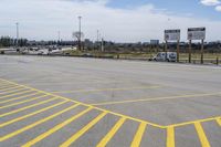 a parking lot with lots of yellow lines painted on it in front of a blue and white sky with clouds