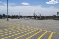 a parking lot with lots of yellow lines painted on it in front of a blue and white sky with clouds