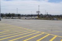 a parking lot with lots of yellow lines painted on it in front of a blue and white sky with clouds