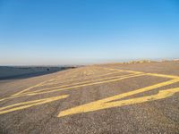 a road with yellow painted arrows on it at the beach in summertime or fall