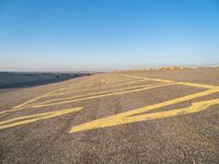 a road with yellow painted arrows on it at the beach in summertime or fall