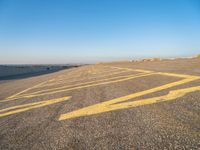 a road with yellow painted arrows on it at the beach in summertime or fall