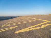 a road with yellow painted arrows on it at the beach in summertime or fall