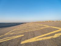 a road with yellow painted arrows on it at the beach in summertime or fall