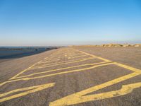 a road with yellow painted arrows on it at the beach in summertime or fall