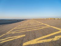 a road with yellow painted arrows on it at the beach in summertime or fall