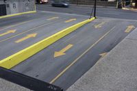 a yellow painted handrail is at the side of a street, with parking spaces on each side