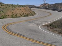 the yellow double striped road is winding into the distance, with a bridge in the background