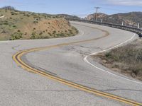 the yellow double striped road is winding into the distance, with a bridge in the background