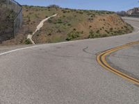 the yellow double striped road is winding into the distance, with a bridge in the background