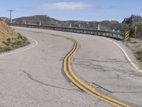 the yellow double striped road is winding into the distance, with a bridge in the background