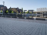 a young boy running across a brick paved sidewalk next to the water and a city