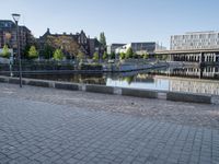 a young boy running across a brick paved sidewalk next to the water and a city