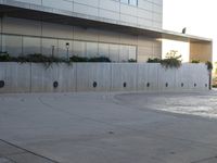 a young boy doing tricks on a skateboard at the park and the building with the reflection