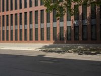 a young man riding a skateboard next to a tall brick building with windows on top