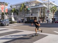 a young man rides his skateboard along the crosswalk on a city street in california