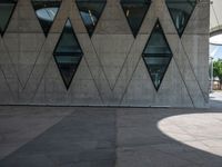 a young man is walking by some nice architecture, with many smaller windows and some people