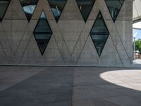 a young man is walking by some nice architecture, with many smaller windows and some people