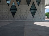 a young man is walking by some nice architecture, with many smaller windows and some people