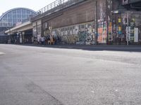 young people are riding skateboards down the city street in front of a graffiti covered wall