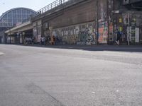 young people are riding skateboards down the city street in front of a graffiti covered wall