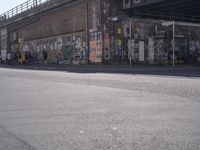 young people are riding skateboards down the city street in front of a graffiti covered wall