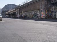 young people are riding skateboards down the city street in front of a graffiti covered wall