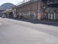 young people are riding skateboards down the city street in front of a graffiti covered wall