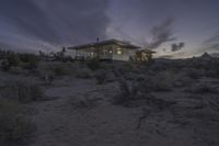 an off - grid home sits in the desert at sunset with its front porch open