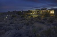 a house in the middle of a desert area at night with an outside dining and bar