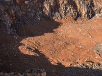 a mountain bike rider stands next to a mountain with a dirt pit in the foreground