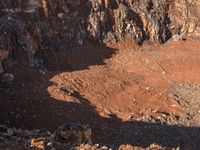 a mountain bike rider stands next to a mountain with a dirt pit in the foreground