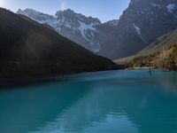 a bright blue lake and mountains during the day and with trees on it with the sky