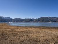 the view of a lake and mountains with boats on it from a distance, as if on land