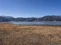 the view of a lake and mountains with boats on it from a distance, as if on land