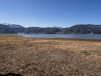 the view of a lake and mountains with boats on it from a distance, as if on land