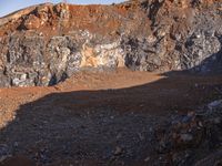 an open cut in the mountains with some dirt and rubble on the bottom ground near it