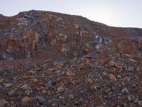 a hill full of rubble and rocks on top of a rocky slope with clouds in the sky