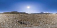 a desert scene with the moon in the distance in an open field with some mountains behind it